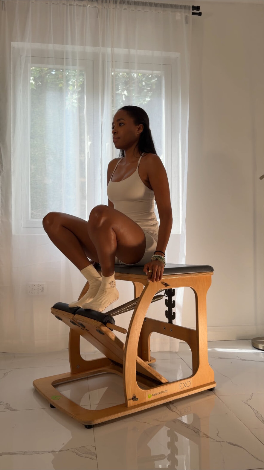 Imani Angus, founder of Align Pilates Studio, seated on the Pilates chair